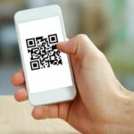 Hand holding smartphone with QR code on the screen